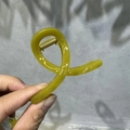 Detail view of large olive green translucent hair claw clip with golden metal spring - 8cm Small Cross / Yellow-Green