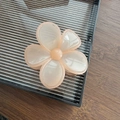 Gros plan d'une grande pince à cheveux fleur en résine rose pêche sur un plateau - Blanc avec Bord Rose Orangé