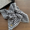 Dettaglio scrunchie a righe con etichetta metallica dorata fatta a mano su legno scuro - Stile Sciarpa