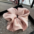 Gros plan d'un chouchou en satin rose avec texture perlée sur un élégant plateau noir - Rose