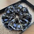Dettaglio dell'elastico per capelli a fiori blu con bordo viola su vassoio a onde - Blu Nero Floreale Grande