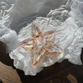 Détail macro d'une pince à cheveux étoile irisée avec ressort doré sur papier blanc - Orange éclatant