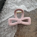 Detalle de una pinza para el cabello rosa claro con forma de lazo y resorte dorado - Rosa