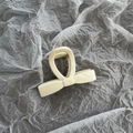 Detailed view of a cream bow shark hair claw clip with golden metal spring - Small Beige White