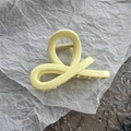 Detalle de una pinza para el cabello amarillo crema con mecanismo de resorte de metal dorado - Amarillo