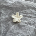 Detail of a pearlescent white flower hair claw clip with golden metal spring - White