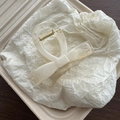 Detail view of a creamy white bow hair claw clip with a polished gold metal spring - White