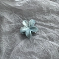 Detailed top view of light blue marble textured flower hair claw clip on white paper - Blue