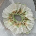 Detail eines großen, gestuften Plaid-Scrunchie aus zartem, pastellgrünem Organzastoff - Grün