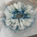 Detailansicht eines karierten Haargummis mit geschichteten weißen Organza-Rüschen - Blau