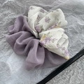 Dettaglio macro di scrunchie floreale plissettato con contrasto viola e tessuto morbido - Viola