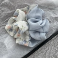 Dettaglio di un grande scrunchie in tessuto azzurro con una delicata stampa floreale - Blu