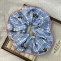 Detail of blue checkered scrunchie with cute dog pattern and pink stitched edges - Blue