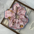 Detail of pink plaid dachshund scrunchie with blue stitched edges on a tray - Pink