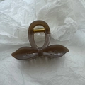 Detailed close-up of a brown amber bow hair claw clip with golden metal spring - Brown