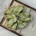 Close-up of green checkered scrunchie with cartoon dachshund prints in a gift box - Green
