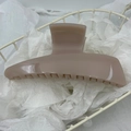 Dettaglio di una pinza per capelli in acrilico marrone chiaro con finitura lucida e denti antiscivolo - Caffè Chiaro