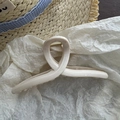 Detail of a large cream hair claw clip on a straw hat with a blue ribbon background - Off White