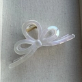 Close-up of iridescent bow hair claw clip with mother-of-pearl finish and gold metal spring - White