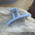 Macro shot of a light blue matte rectangle hair claw clip on soft white paper - Blue