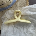 Close-up of a cream-colored large cross hair claw clip on a stylish paper background - Yellow