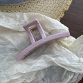 Close-up of a matte lavender rectangular hair claw clip on a stylish fabric background - Pink