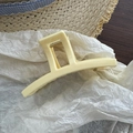 Detail view of a cream-colored matte hair claw clip on a summer vacation style background - Yellow