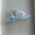 Detail shot of iridescent mermaid bow hair claw clip with golden metal spring - Blue