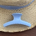 Primer plano de pinza para el pelo azul claro con costuras blancas en sombrero de paja - Azul