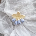 Detail der matten Haarklammer mit cremefarbenen Tulpenblättern und blauen Blüten - Lila