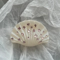 Detail van parelwitte schelp haarklem met roze strass vlinder en ster versieringen erop - Wit