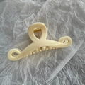 Dettaglio di un grande fermaglio per capelli a onda crema con molla in metallo dorato - Beige