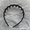 Dettaglio del cerchietto nero ondulato con denti fini per un effetto acconciatura alta - Nero Lucido