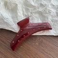 Détail d'une pince à cheveux bordeaux translucide avec strass rouges sur bois - Rouge