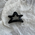 Dettaglio di un fermaglio per capelli nero lucido a forma di stella su sfondo bianco - Nero Stella a Cinque Punte