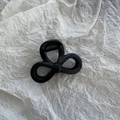 Close-up of glossy black star-shaped hair claw clip on textured beige background - Black Bowknot