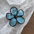Detail view of flower-shaped hair claw with blue plaid pattern and black borders - Flower Shape