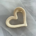 Primer plano de pinza de pelo de corazón crema con muelle dorado sobre fondo de tul - Pinza de Corazón