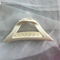 Detail view of large cream-colored silicone hair claw clip with gold metal spring for women - White Triangle