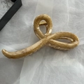 Makroaufnahme der großen Haarklammer in Marmoroptik mit goldener Metallfeder - Holzmaserung Wellenlinie-Stil