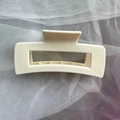 Close-up of a cream rectangular matte hair claw clip on soft white mesh fabric - White Square