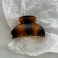 Detailed view of the smooth tortoiseshell amber fan-shaped hair claw on white paper - Tortoise