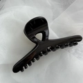 Close-up of a glossy black French hair claw clip on soft white fabric background - Bright Black