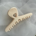 Close-up of a large cream-colored glossy hair claw clip on soft white tulle fabric - Glossy White