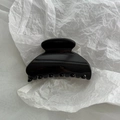 Dettaglio di una molletta per capelli nera lucida con design curvo e denti fitti - Nero Lucido