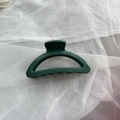 Detail shot of a large forest green silicone shark hair claw clip on white fabric - Dark Green Semi-circle