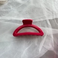 Close-up of a large magenta soft silicone hair claw clip on a white tulle fabric background - Red Semi-circle