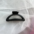 Detailed top view of a large glossy black silicone hair claw clip on white fabric - Black Semicircle