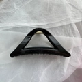 Macro detail of glossy black triangular hair claw clip with a strong golden metal spring - Black Triangle