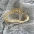 Close-up of wavy cream amber hair claw clip with golden metal spring on white paper - Cloud Yellow Two-tone Hair Clip